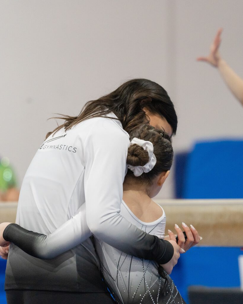 thrive gymnastics aurora ontario coach congratulates gymnast at competition